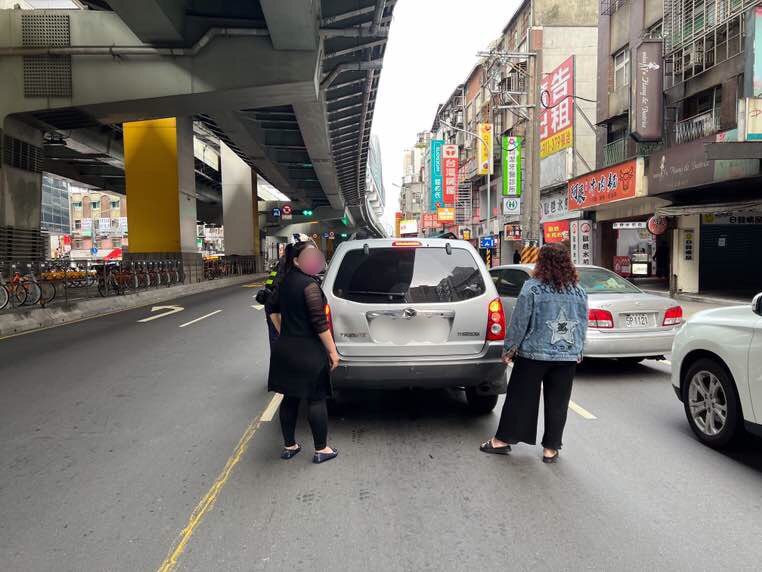 圖片說明：景安所員警見一輛自小客車停駛在馬路中央，由2名女性乘客下車引導後方車輛閃避，立即上前協助。（記者宋紹誠翻攝）