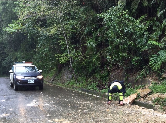 圖片說明：涂廷豐警員徒手搬移坍塌石塊至路旁，以維護用路安全。（記者葉鈞宇翻攝）