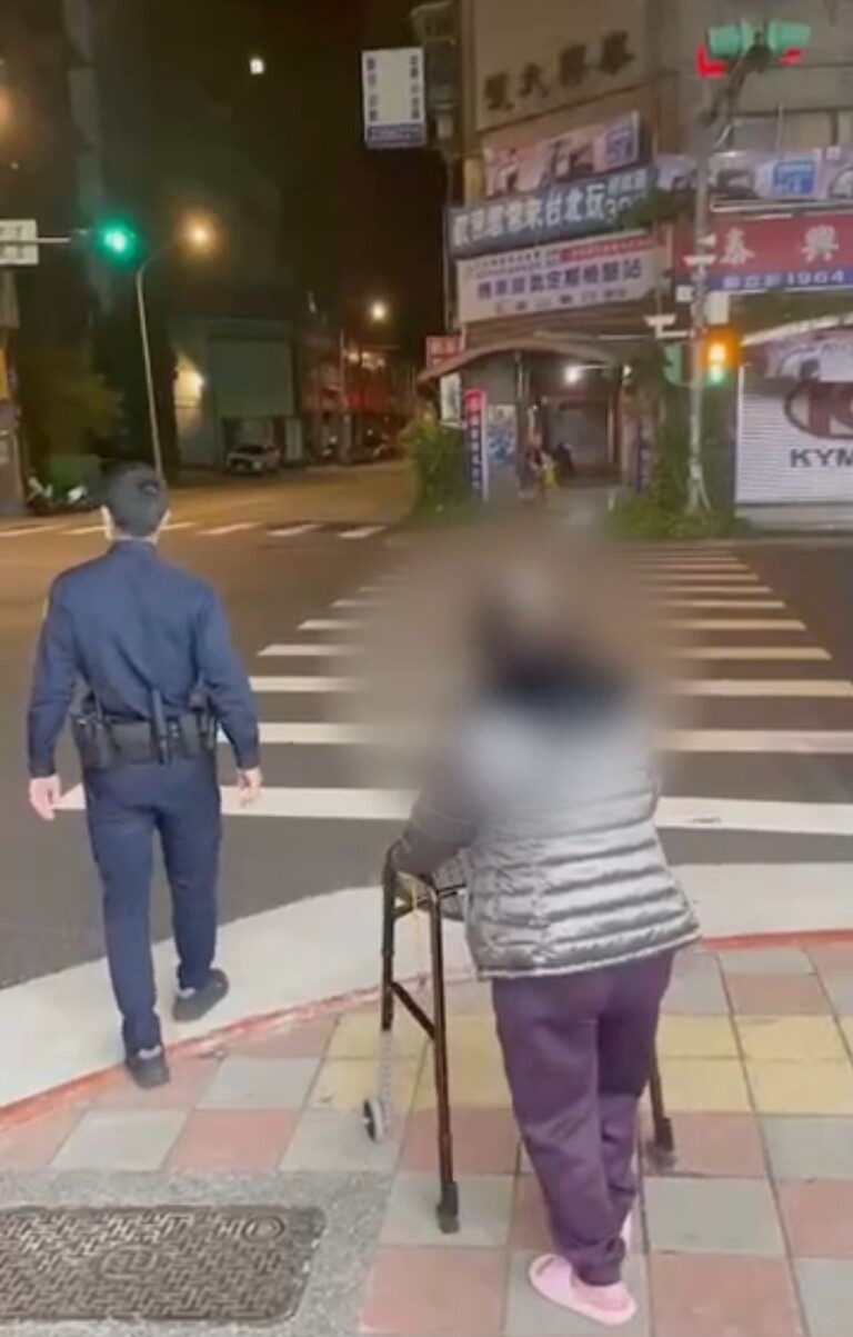 圖片說明：龍山派出所警員張哲源護送陳老太太過馬路。（記者徐煜勝翻攝）