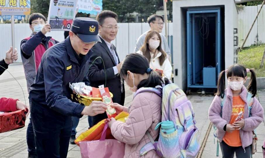 南港分局長周哲民率同仁至東新國小守護學童安全，並與東新國小校長李家旭共同發放新春小禮品給學童們。（記者薛秀蓮翻攝)